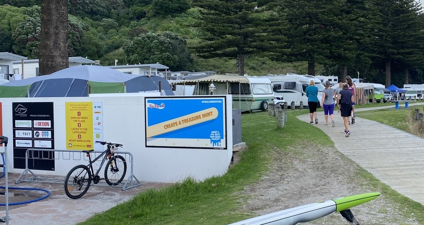 Tip Top Challenge Sticks advertising sign on the wall with a campground in the background