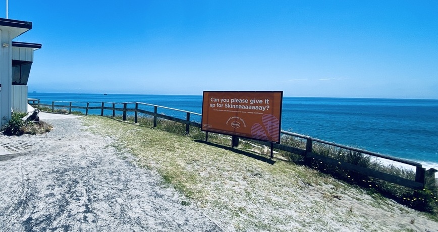 Skinny mobile advertising sign at the beach on a clear sunny day